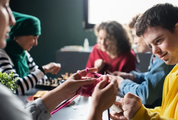 Group of people engaged in crafting and board games in a community home service setting by A Different World.