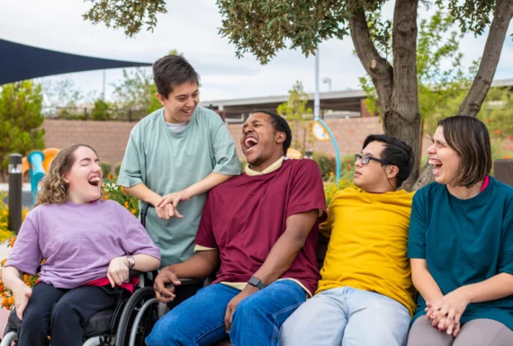 Diverse group of individuals sharing a joyful moment outdoors with supportive home service by A Different World.